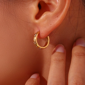 Close-up of gold-plated chunky C-shaped hoop earrings with inlaid sparkling zircons