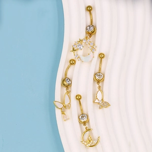 Detailansicht von vier goldenen Bauchnabelpiercings mit Schmetterling, Mond und Opal