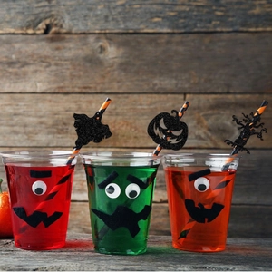 Halloween party drink cups with orange striped straws and glitter spooky toppers
