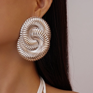 Détail macro de grandes boucles d'oreilles spirales argentées portées par un mannequin
