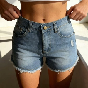 Detailed close-up of high-waist light blue denim shorts with frayed edges and distressed rips