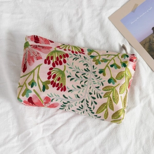Detail view of floral embroidered portable makeup bag with smooth metal zipper