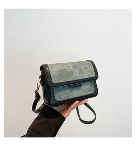 Detail of a chic flap bag with black and grey-green denim texture and metal hardware
