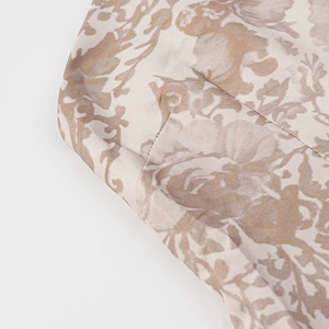 Detail of beige satin fabric featuring floral prints and soft glossy texture