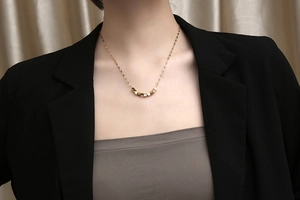 Detail of model wearing a gold titanium necklace with seven small square metal beads