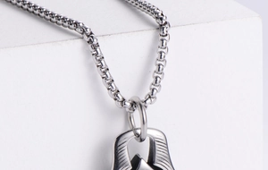 Detail of silver box chain and geometric textured pendant in polished stainless steel