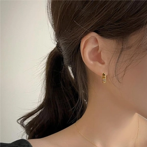 Close-up of elegant gold anchor chain earrings worn by model for a modern fashion look