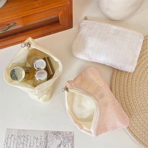 Detailed view of quilted makeup bags in white, yellow, and pink with metal zippers
