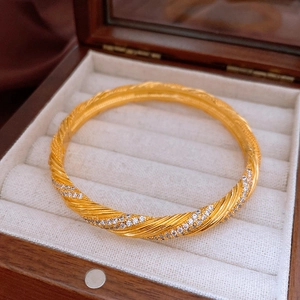 Detailed macro of a vintage gold-plated twisted bangle with shimmering cubic zirconia