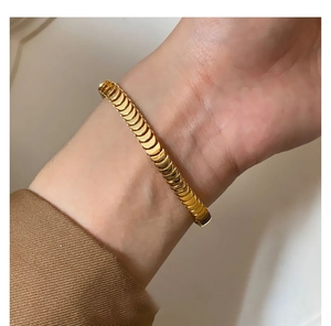 Detail of gold fish scale bracelet featuring interlocking semicircular metal links