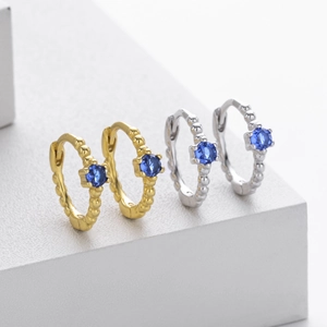 Detailed view of silver and gold beaded hoop earrings with blue zircon center stones