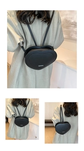 Detail of black heart-shaped backpack featuring embossed letters and sleek silver metal logo