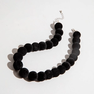 Détail d'un collier de perles noires floquées avec rallonge et fermoir en métal argenté