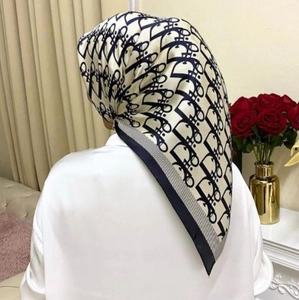 Detailed view of beige and black monogram crinkle scarf draped over model's shoulders
