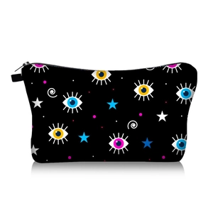 Close-up of a trapezoidal makeup bag with colorful evil eye and star patterns on black fabric