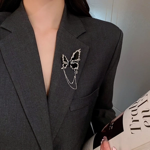 Élégante broche papillon noire avec chaînes argentées épinglée sur un blazer gris chic