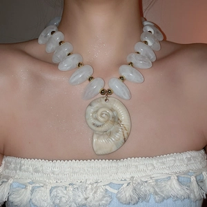 Detail einer Boho-Halskette mit großen weißen Perlen und natürlichem Muschel-Anhänger