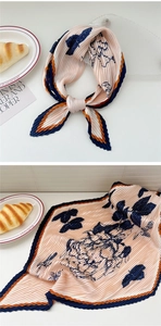 Detail of pleated floral silk scarf with peach background and navy flower patterns