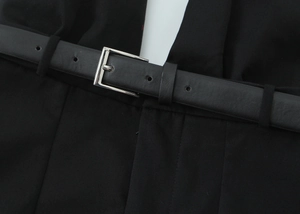 Detail of a black leather belt with silver square metal buckle on a black fabric top