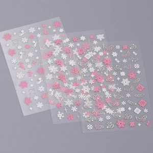 Close-up of pink and silver snowflake and angel nail art stickers on a gray background
