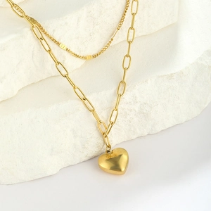 Macro shot of gold double-layer necklace with paperclip chain and 3D heart pendant