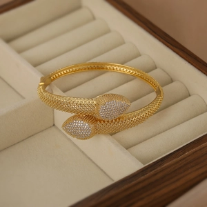 Offenes Schlangenarmband in Gold mit Zirkonia-Besatz und gewebter Metallstruktur