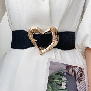 Close-up of a wide black elastic waist belt with a polished gold heart-shaped buckle
