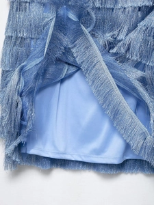 Detailed close-up of blue fringe tassels and matching lining on a stylish mini dress
