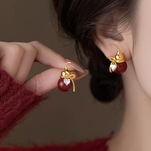 Gold plated gourd earrings with red stones and heart zircon on a female model