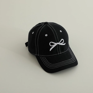 Détail d'une casquette noire avec broderie nœud blanc et surpiqûres contrastantes
