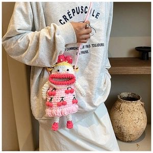 Close-up of pink handmade crochet phone bag with cartoon face and cherry details