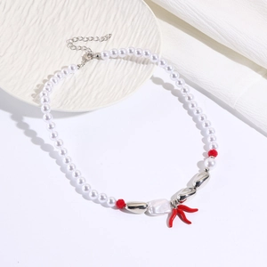 Detail of multi-layered pearl necklace with red coral pendant on white ceramic plate