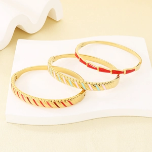 Detailed view of 18K gold plated bangles with colorful enamel stripes on white stand