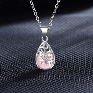 Macro shot of silver teardrop pendant necklace with pink crystal and hollow pattern