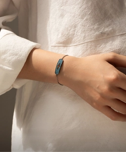 Detail of s925 silver bracelet with blue crystal and star cutout on a black chain