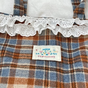 Macro shot of blue plaid wool tote with embroidered lace edge and Happy patch detail