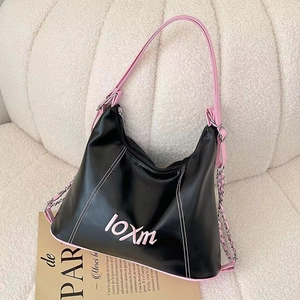 Close-up of black and pink tote bag with metal chain on a soft white sofa and magazine
