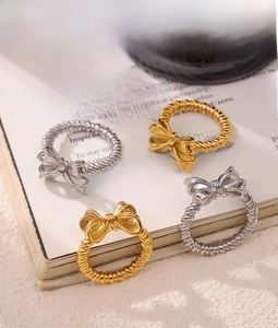 Dettaglio di anelli a fiocco oro e argento con fascia a treccia su pagine di libro
