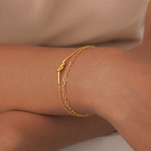 Detail of a gold double-layer knotted bracelet on a woman wrist with sleek metal texture