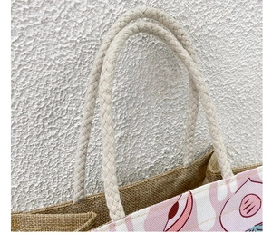 Detailed close-up of woven rope handle and natural jute fiber texture on canvas tote bag