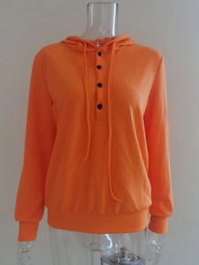Detalle de textura acanalada y botones negros en sudadera con capucha naranja brillante