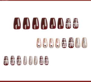 Detail of red and white ballerina press-on nails with reindeer and snowflake patterns