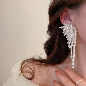 Close-up of dangling white pearl tassel earrings on model with elegant floral design