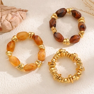 Detail view of bohemian resin and irregular metal bead stretch bracelets in amber and gold