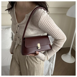 Close-up of wine red leather underarm bag featuring a vintage golden metal clasp