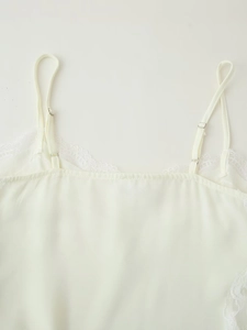 Close-up of adjustable straps and lace trim on a white satin camisole top