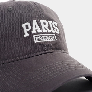 Detail of dark grey baseball cap featuring premium white 3D embroidery of PARIS FRENCH