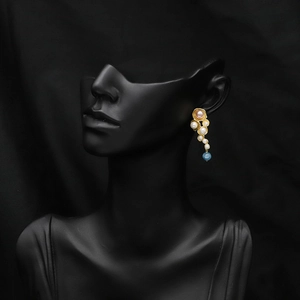 Natural pearl earrings with blue gemstone drops on black mannequin stand for elegant look