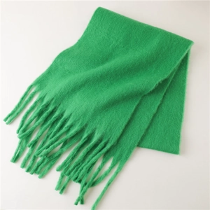 Détail de l'écharpe en maille mohair verte montrant la texture douce et les pompons