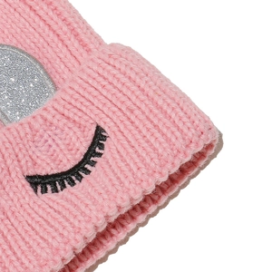 Détail macro du bonnet en maille rose avec paillettes argentées et cils brodés mignons